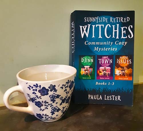 paperback book of Sunnyside retired witches books 1-3 by Paula Lester with cup
